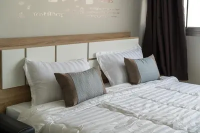 a large white bed with pillows on top of it at Popular Condo Muangthong by Khun Eve in Nonthaburi