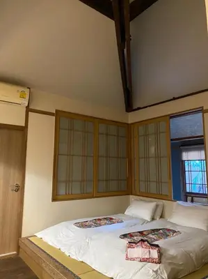 a large bed in a room with windows at MAYU Bangkok Japanese Style Hotel in Bangkok