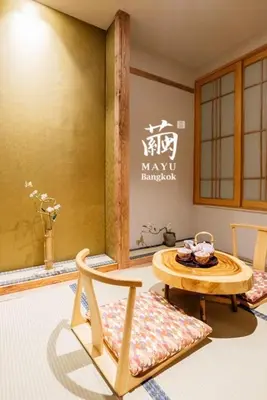 a room with a table and chairs in a room with a sign at MAYU Bangkok Japanese Style Hotel in Bangkok