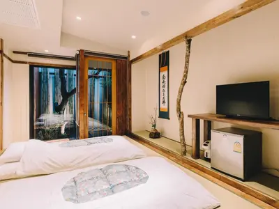a bedroom with a bed and a flat screen tv at MAYU Bangkok Japanese Style Hotel in Bangkok