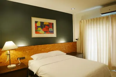 a bedroom with a white bed and a table with a lamp at The 92 Residence in Bangkok