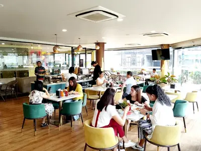 a group of people sitting at tables in a restaurant at Siri Oriental Bangkok Hotel in Bangkok