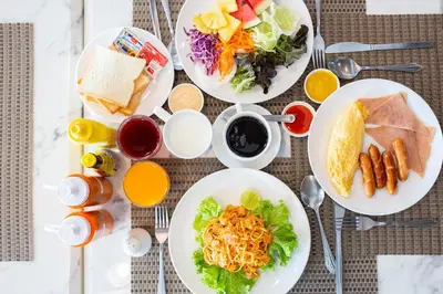 a table topped with plates of food and drinks at Spittze Hotel Pratunam in Bangkok
