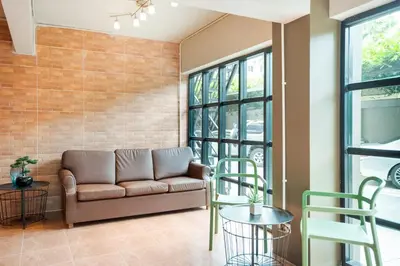 a living room with a couch and tables and windows at Matini Ratchada 32 in Bangkok