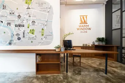 an office with a wooden desk and a map at Warm Window Silom in Bangkok
