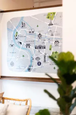 a map hanging on a wall with a plant at Warm Window Silom in Bangkok