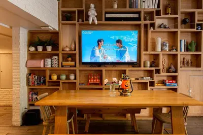 a television in a living room with a wooden table at Simply Sleep Hostel in Bangkok