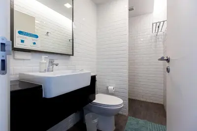 a white bathroom with a sink and a toilet at Simply Sleep Hostel in Bangkok