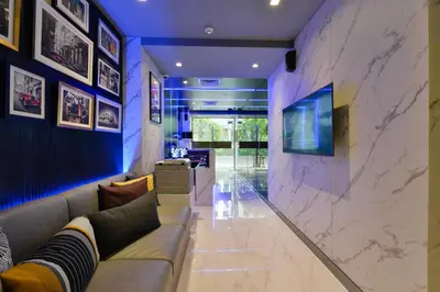 a living room with a couch and a tv on a wall at Syama Nana in Bangkok