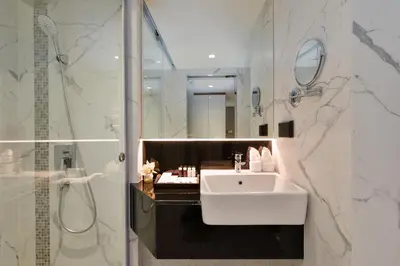 a white bathroom with a sink and a shower at Syama Nana in Bangkok