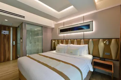 a bedroom with a large bed and a tv on the wall at Syama Nana in Bangkok