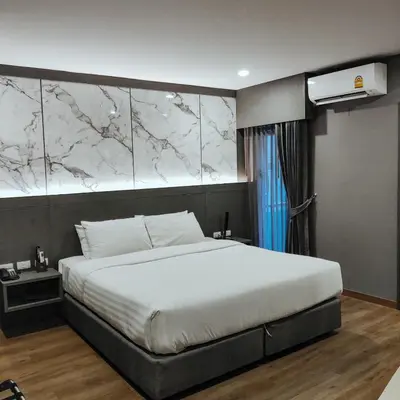 a bedroom with a white bed with a marble wall at Hyde Park Hotel Bangkok in Bangkok