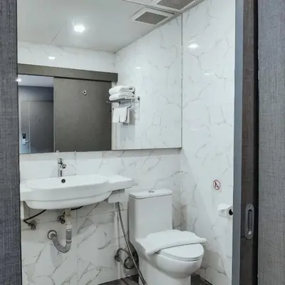 a white bathroom with a toilet and a sink at Hyde Park Hotel Bangkok in Bangkok