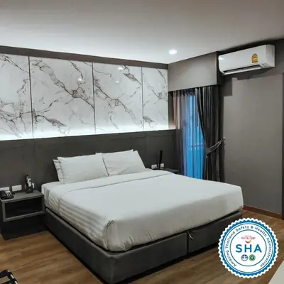 a bedroom with a white bed with a marble wall at Hyde Park Hotel Bangkok in Bangkok