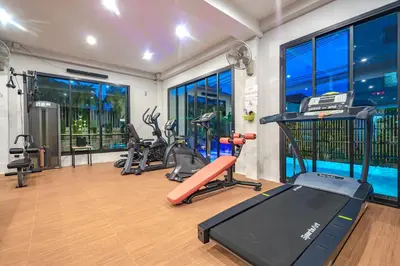 a gym with exercise equipment and a swimming pool at Penyos Residence in Bangkok