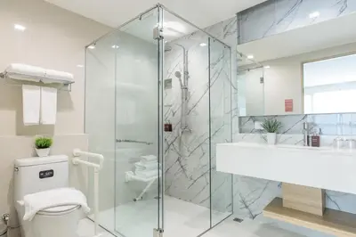 a bathroom with a shower and a toilet and a sink at Alix Bangkok Hotel in Bangkok