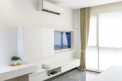 a white bathroom with a sink and a tv at Alix Bangkok Hotel in Bangkok
