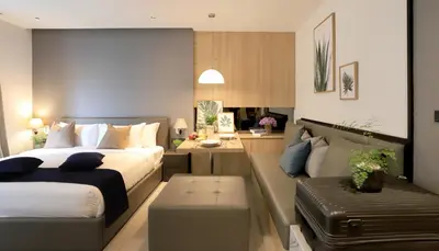 a bedroom with two beds and a desk and a couch at Alix Bangkok Hotel in Bangkok