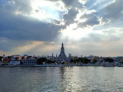 a view of a city from the water with the sun shining at Arun Residence in Bangkok