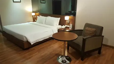 a bedroom with a bed and a chair and a table at S.D. Avenue Hotel in Bangkok