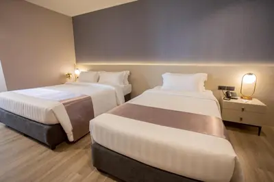a hotel room with two beds and a table with a lamp at S.D. Avenue Hotel in Bangkok