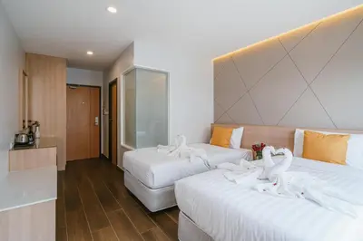 two beds in a hotel room with white towels on them at Season Place in Bangkok
