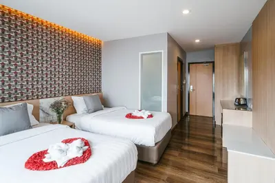 two beds in a hotel room with red and white pillows at Season Place in Bangkok