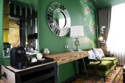 a green room with a table and a mirror at Dhevi Bangkok Hotel in Bangkok