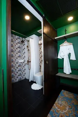 a bathroom with a shower and a toilet and green walls at Dhevi Bangkok Hotel in Bangkok
