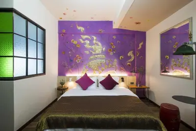 a bedroom with a bed with a purple wall at Dhevi Bangkok Hotel in Bangkok