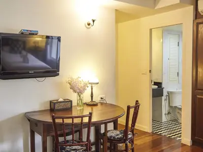 a dining room with a table and a tv on the wall at SSIP Boutique Dhevej Bangkok in Bangkok