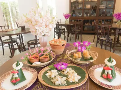 a table with plates of food and flowers on it at SSIP Boutique Dhevej Bangkok in Bangkok