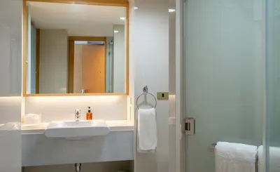 a bathroom with a sink and a mirror and a shower at VELA Dhi GLOW Pratunam in Bangkok