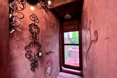 a room with a pink wall with a window at Old Capital Bike Inn - SHA Certified in Bangkok