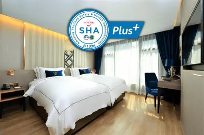 a hotel room with a large white bed and a sign at GLOW Sukhumvit 5 in Bangkok