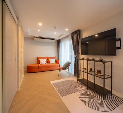 a living room with an orange couch and a television at Triple Four in Bangkok