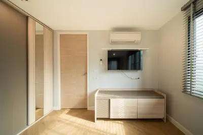 a living room with a cabinet and a tv at Triple Four in Bangkok