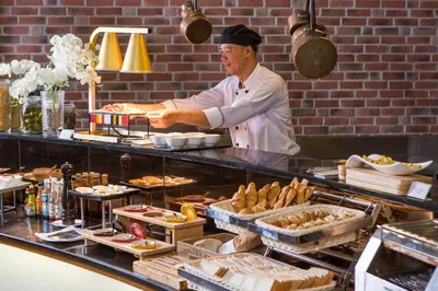 a chef standing in a kitchen preparing food at Amaranta Hotel in Bangkok