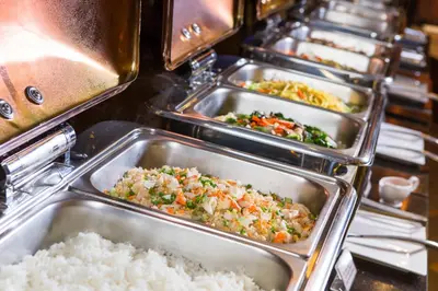 a buffet line of trays of food with rice at Amaranta Hotel in Bangkok