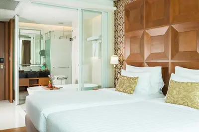 a bedroom with a large white bed and a bathroom at Amaranta Hotel in Bangkok
