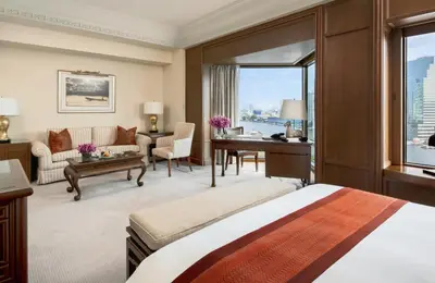 a hotel room with a bed and a desk and a couch at The Peninsula Bangkok in Bangkok