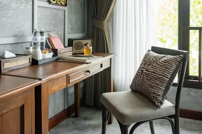 a wooden desk with a chair next to a window at Kasayapi Hotel in Bangkok