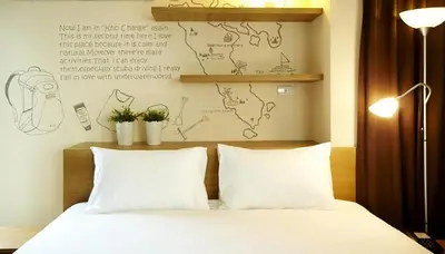 a bed with two pillows and a wall with a map at Loft 77 in Bangkok