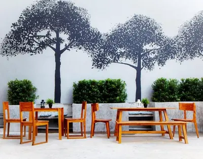 a table and chairs with trees on a wall at Loft 77 in Bangkok