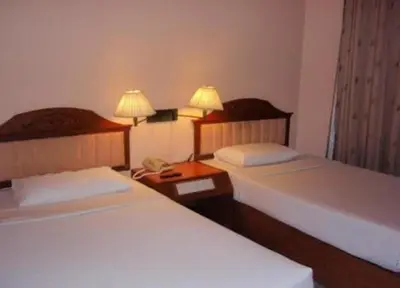 two beds in a hotel room with two lamps at Bangkok City Inn in Bangkok