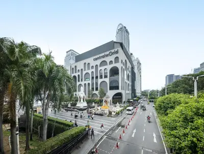 a large building on a city street with palm trees at Platinum Deluxe Shopping Apartments in Bangkok