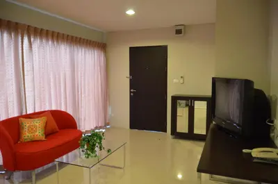 a living room with a red chair and a television at Bangkok Living in Bangkok
