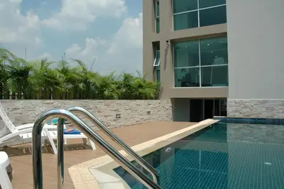 a swimming pool next to a building with a house at Bangkok Living in Bangkok