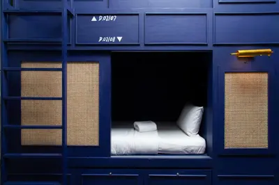 a blue bunk bed with a white pillow in it at Azure Hostel Bangkok in Bangkok