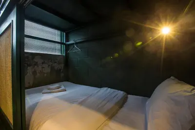 a small bedroom with a bed with a light on it at Azure Hostel Bangkok in Bangkok